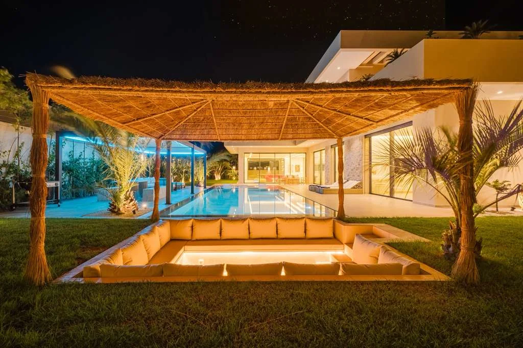 Salon extérieur sous pergola au bord de la piscine